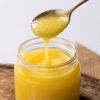 Golden Pure Cow Ghee Pour Pure cow ghee flowing smoothly from a metallic spoon with a rich golden textur